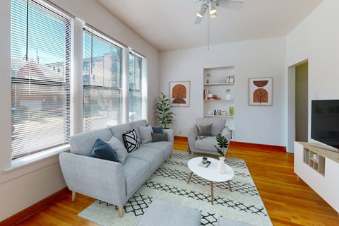 A living room with a grey couch, a white coffee table, and a ceiling fan.
