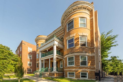 A large, two-story building with a curved corner and a balcony on the second floor.