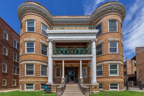 A large, two-story building with a curved corner and a balcony on the second floor.