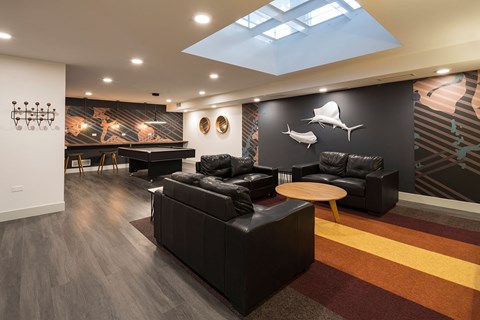 A modern living room with a black couch and a skylight.