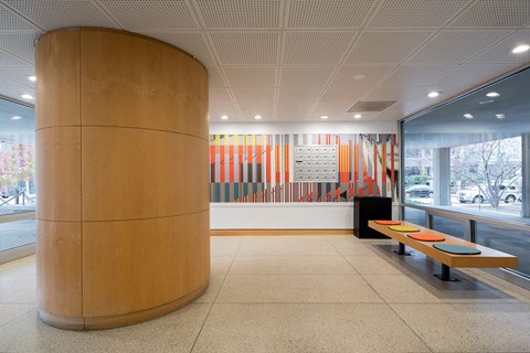 A large wooden column in a room with a bench and a colorful striped wall.