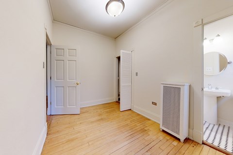 A room with a white door, a white radiator, and a white sink.