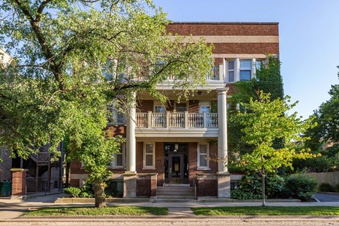 A two-story house with a front porch and a tree in front.