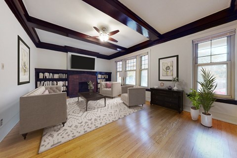 A living room with a grey couch, a coffee table, a rug and a ceiling fan.