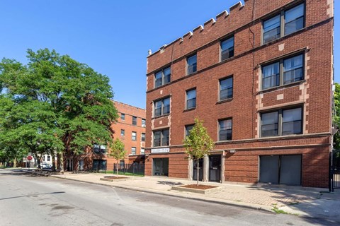 A red brick building with a tree in front of it.