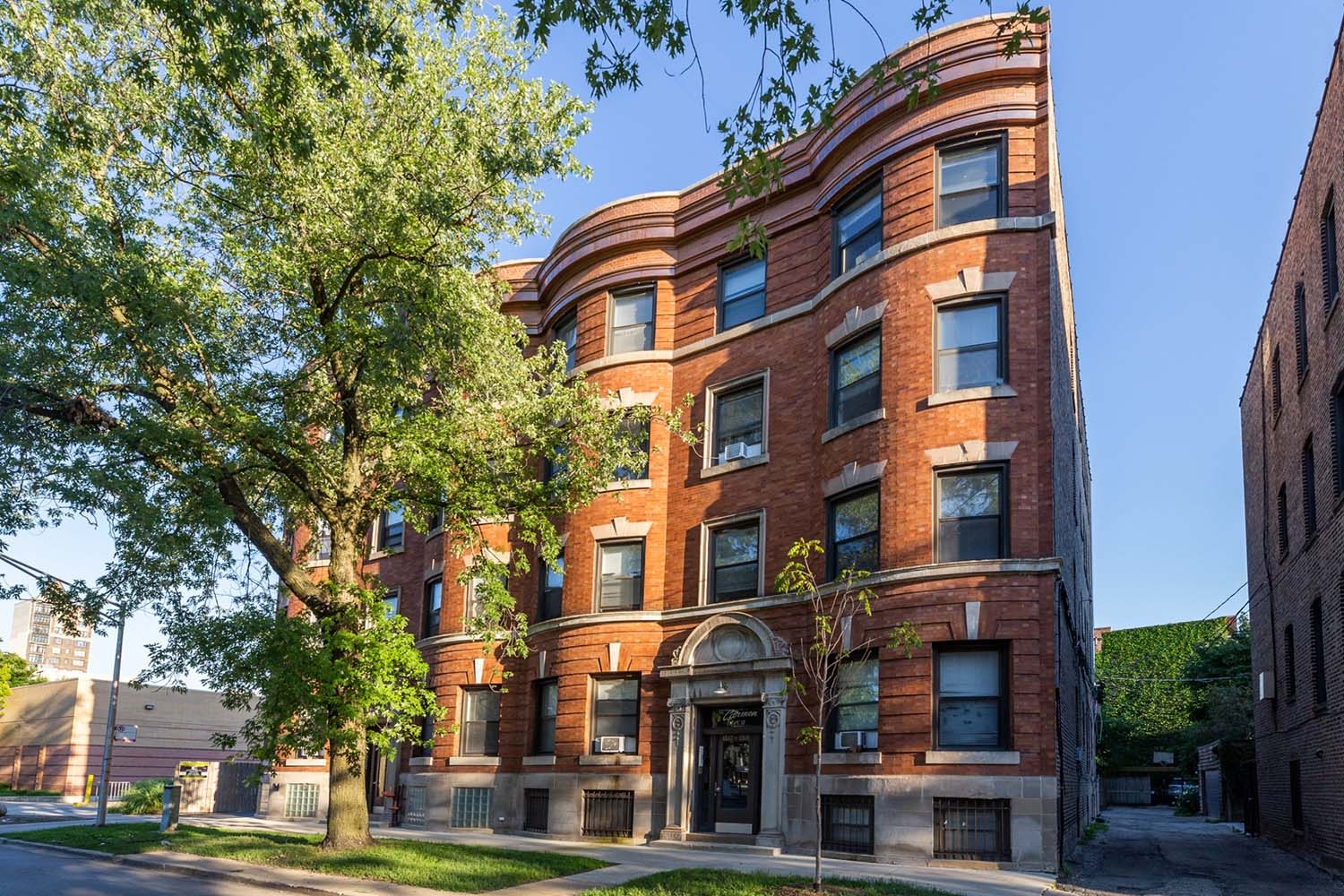 A red brick building with a tree in front of it.