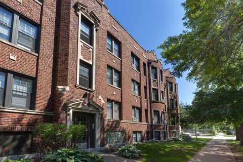 A red brick building with a tree in front.