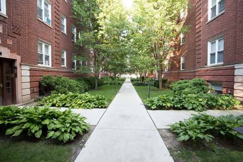 A long concrete walkway leads between two rows of red brick buildings.