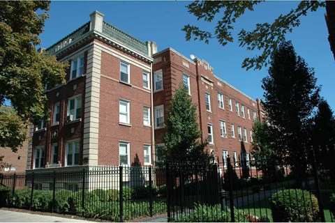 A red brick building with a black fence in front.