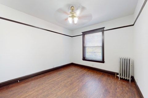 A room with a ceiling fan and a window with blinds.
