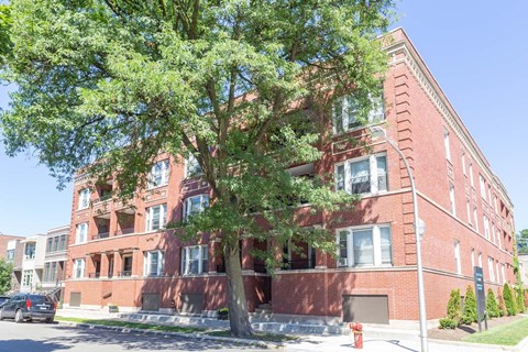 A red brick building with a tree in front.