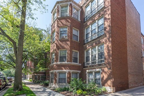 A red brick building with a tree in front of it.