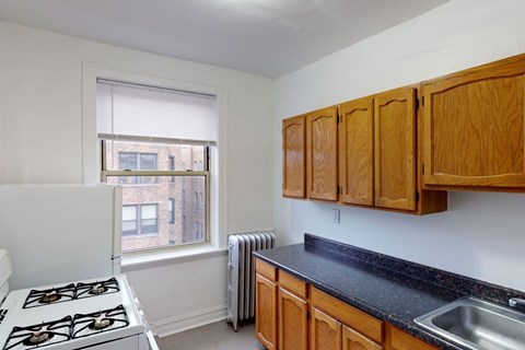 A kitchen with a stove, sink, and window.