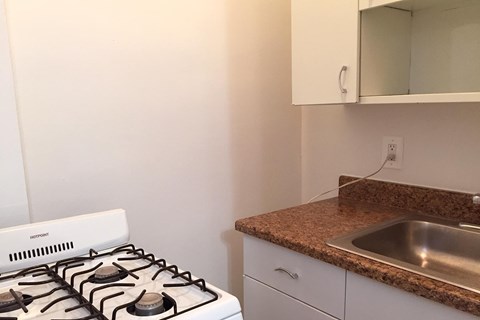 A white gas stove is in a kitchen with a granite counter top.