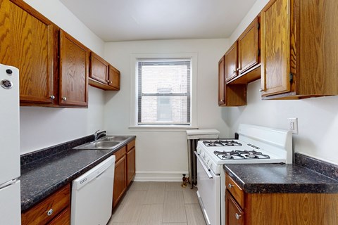 A kitchen with wooden cabinets and black countertops.