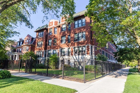 A red brick building with a black fence in front.