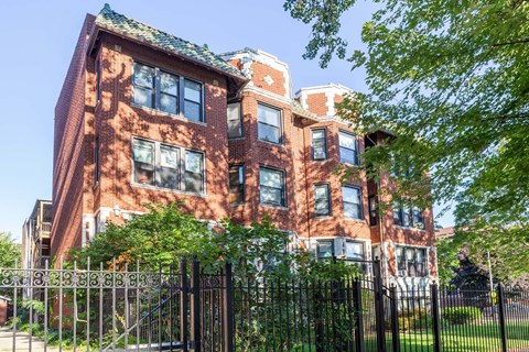A red brick building with a black fence in front.
