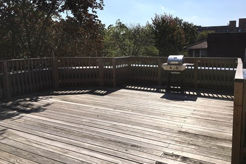 A wooden deck with a grill and a black mat.