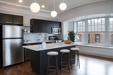 A modern kitchen with a large island and stools.