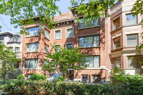 A red brick building with green trees in front.