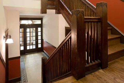 A wooden staircase with a carpeted runner leads up to a door.