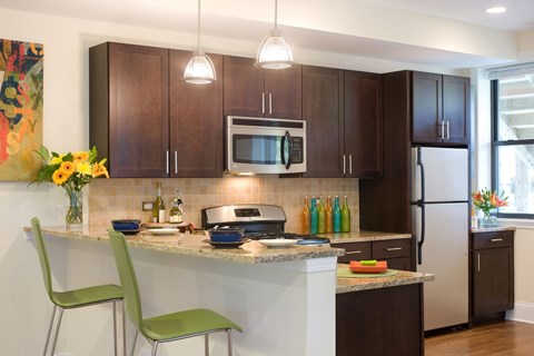 A kitchen with a white countertop and green chairs.