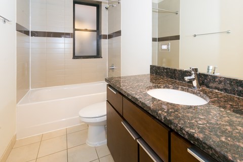 A bathroom with a white toilet and a marble counter top.