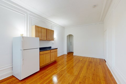 A kitchen with a white refrigerator and wooden cabinets.