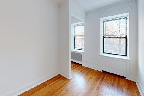 A room with wooden floors and two windows.
