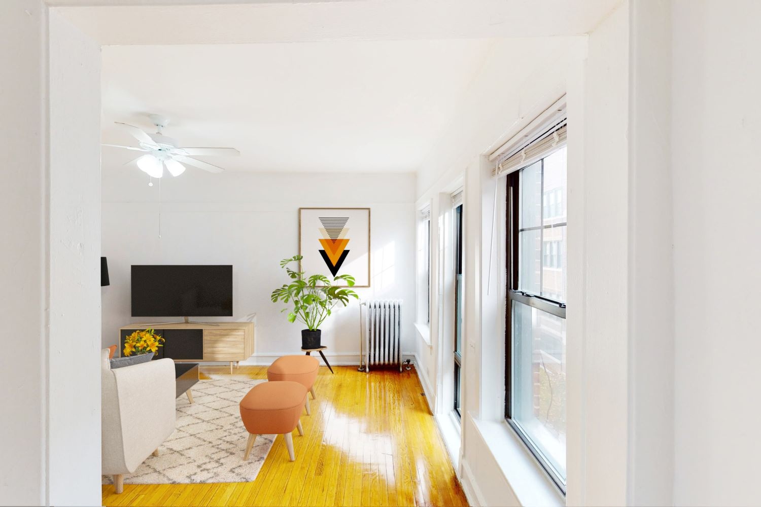 A living room with a television, a plant, and a fan.