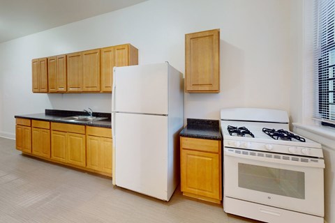 A kitchen with a white refrigerator, white stove, and wooden cabinets.