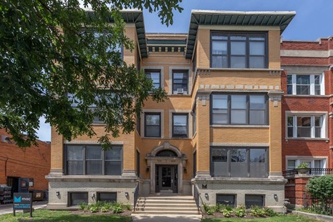 A large, two-story building with a red brick exterior and a black metal fence in front.
