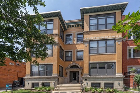 A multi-story building with a brick facade and a large front door.