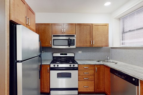 A kitchen with a refrigerator, microwave, oven, and sink.