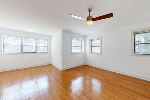 A room with a ceiling fan and three windows.
