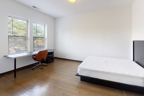 A bedroom with a bed, desk, and chair.