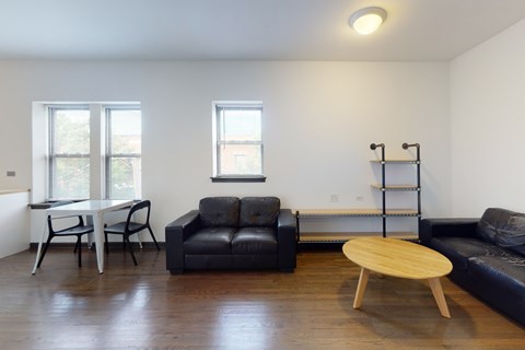 A black couch sits in a living room with a wooden coffee table in front of it.