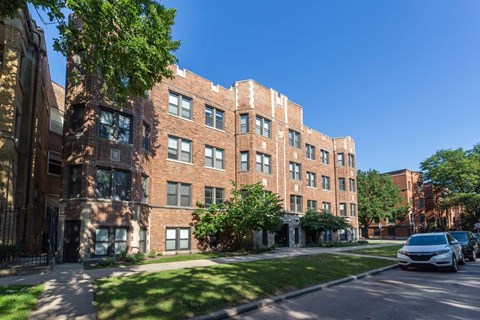 A row of red brick apartment buildings with trees in front.