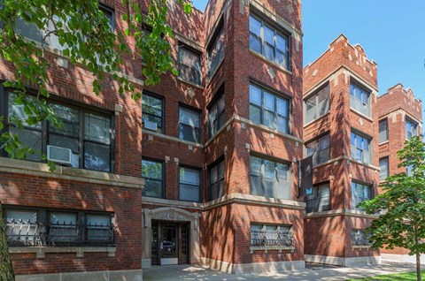 A red brick building with a tree in front.