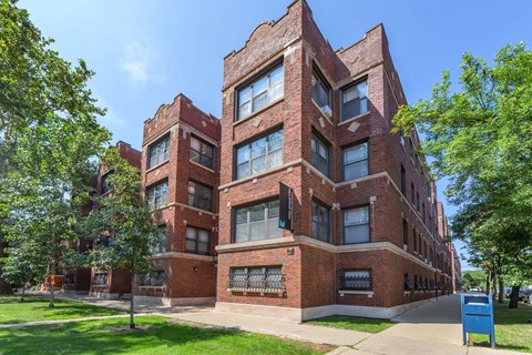 A red brick building with a blue trash can in front of it.