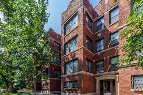 A red brick building with a tree in front.