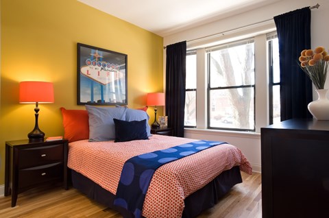 A bedroom with a bed, two lamps, and a painting on the wall.