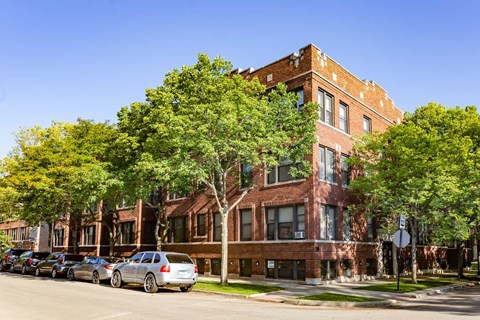 A row of cars parked on a street in front of a brick building.