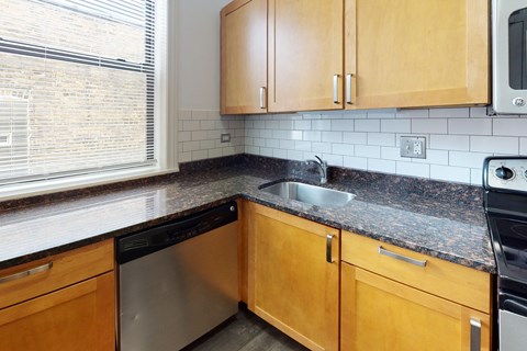 A kitchen with wooden cabinets and a black dishwasher.