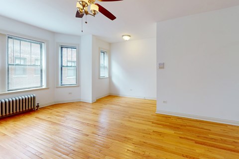 A room with a ceiling fan and wooden floors.