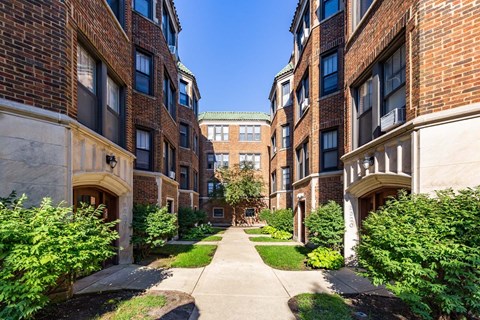 A long, narrow walkway separates two rows of red brick buildings.