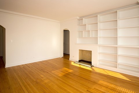 A room with a fireplace and a wall of shelves.
