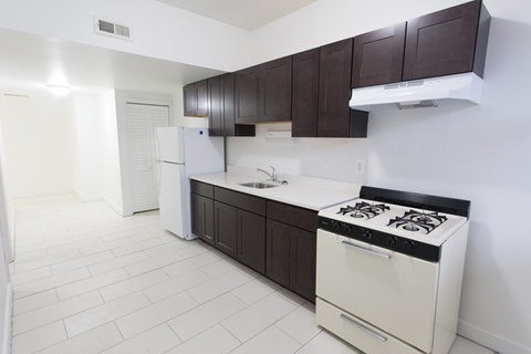 A white stove is in a kitchen with white tile flooring.