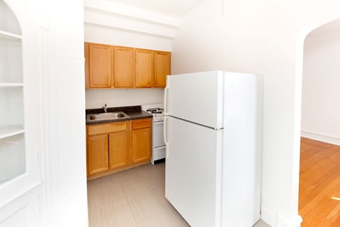 A white refrigerator stands in a kitchen with wooden cabinets.