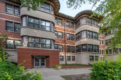 A large, multi-story building with a curved corner and a mix of brick and stone exterior.